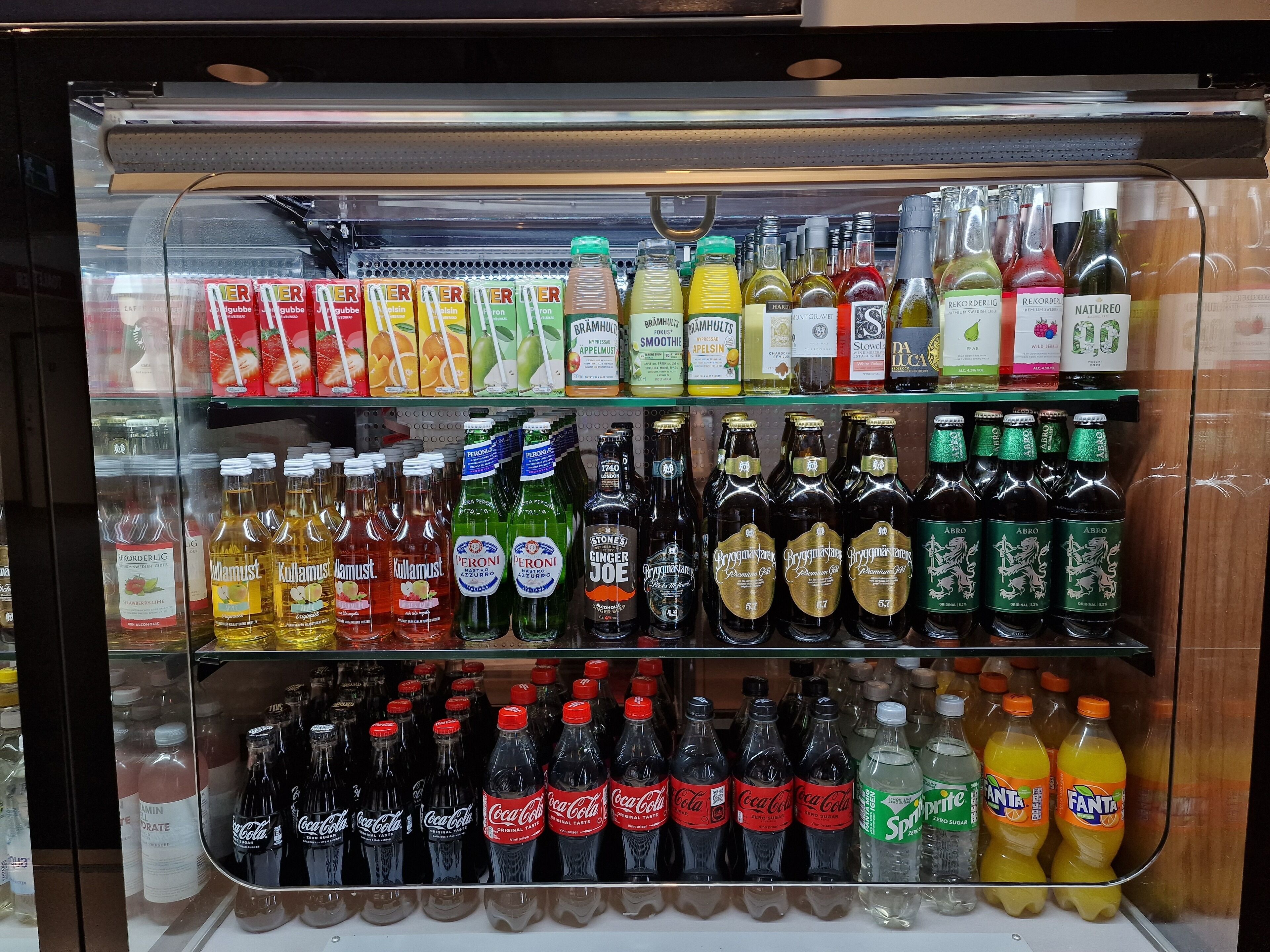 A refrigerated display case with various beverages including sodas, juices, and alcoholic drinks.