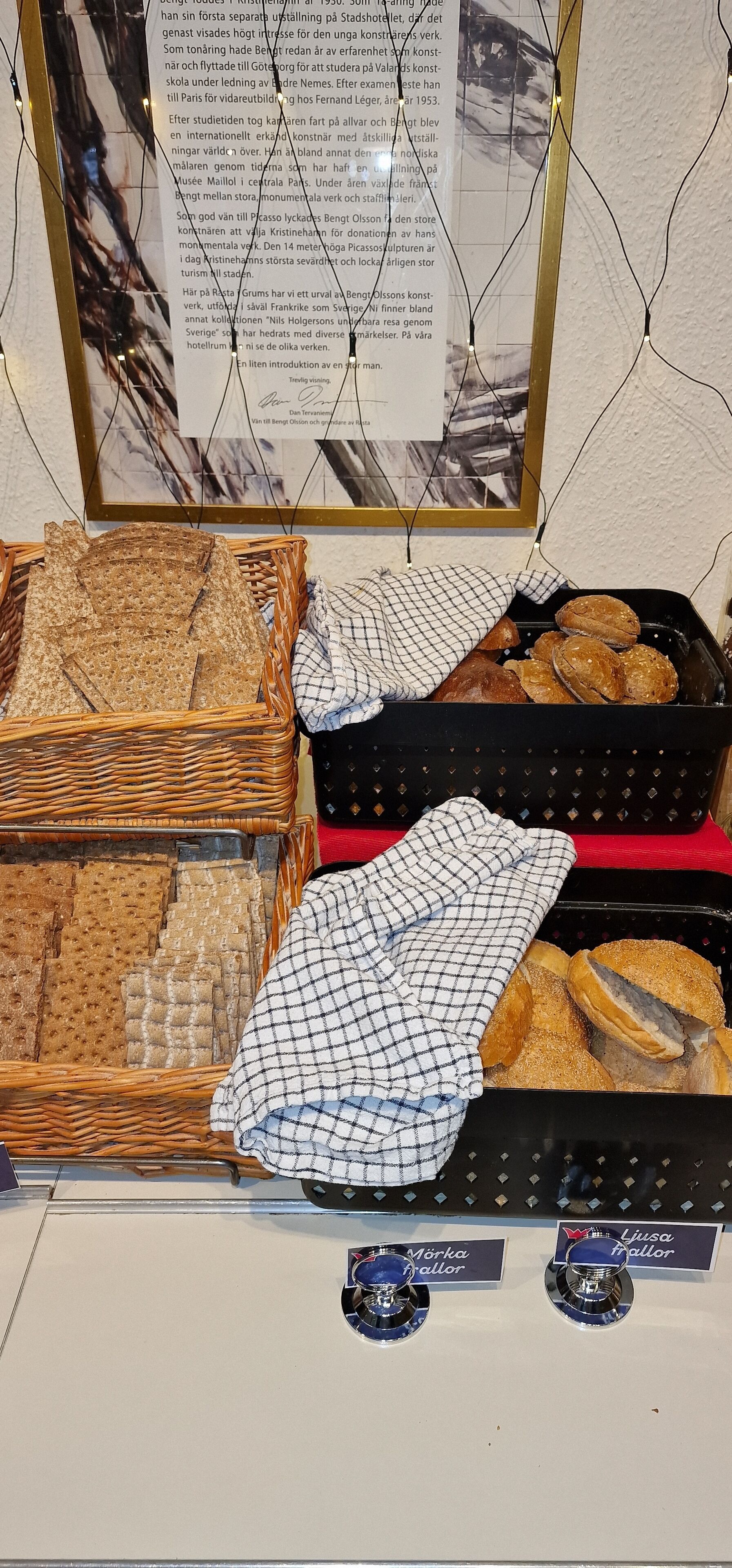 A display of various breads and pastries in wicker baskets and a black tray, with name tags for 'Mörka' and 'Ljusca'.