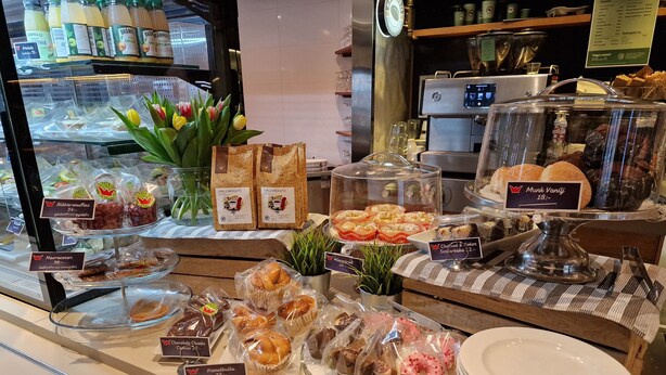 Vitrine de pastelaria com diversos produtos de panificação e doces, incluindo itens identificados como Blåbärsmuffins e Haurecocos.