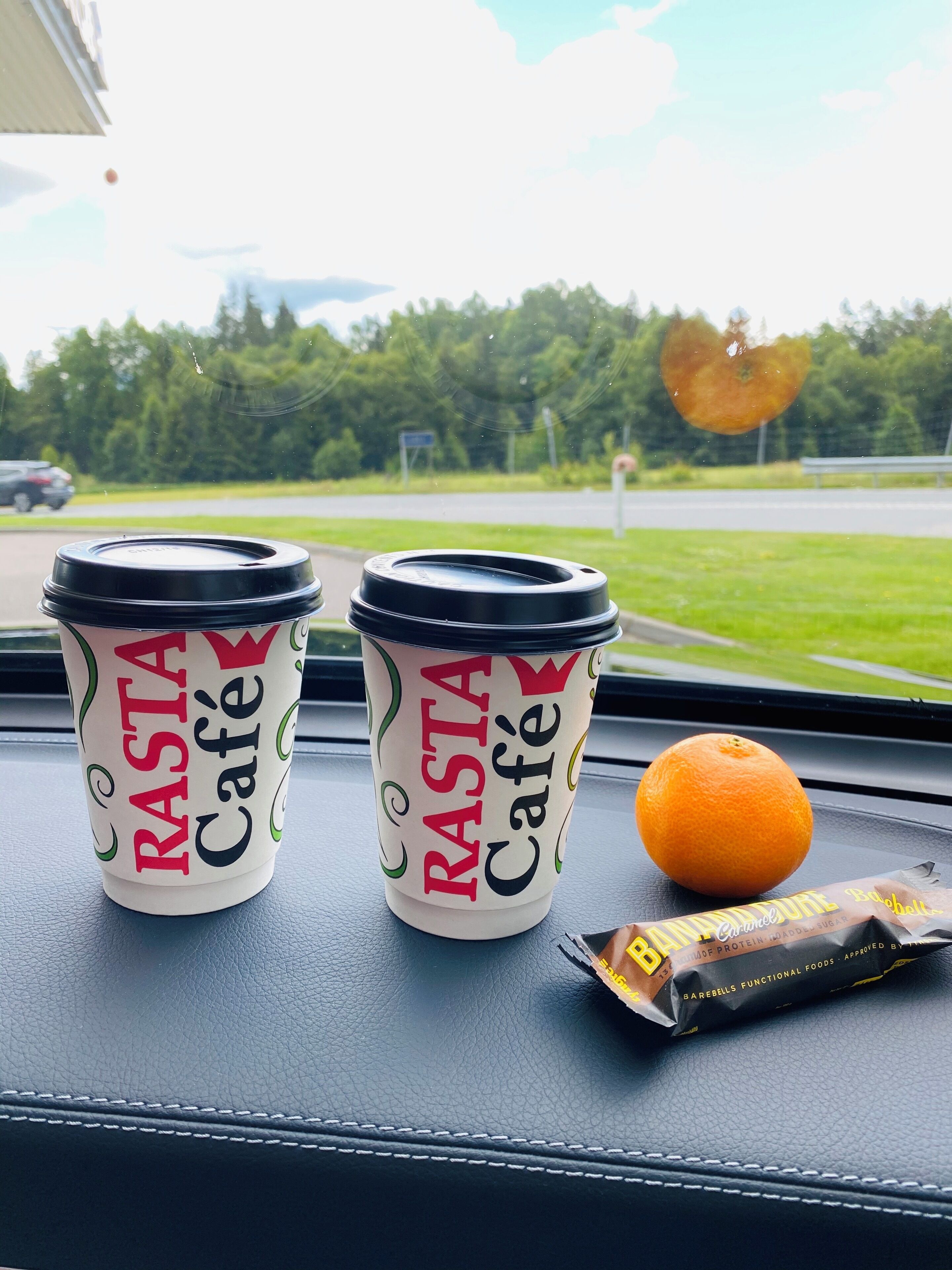Två muggar med Rasta Café-logotypen och en banan på instrumentbrädan i en bil.