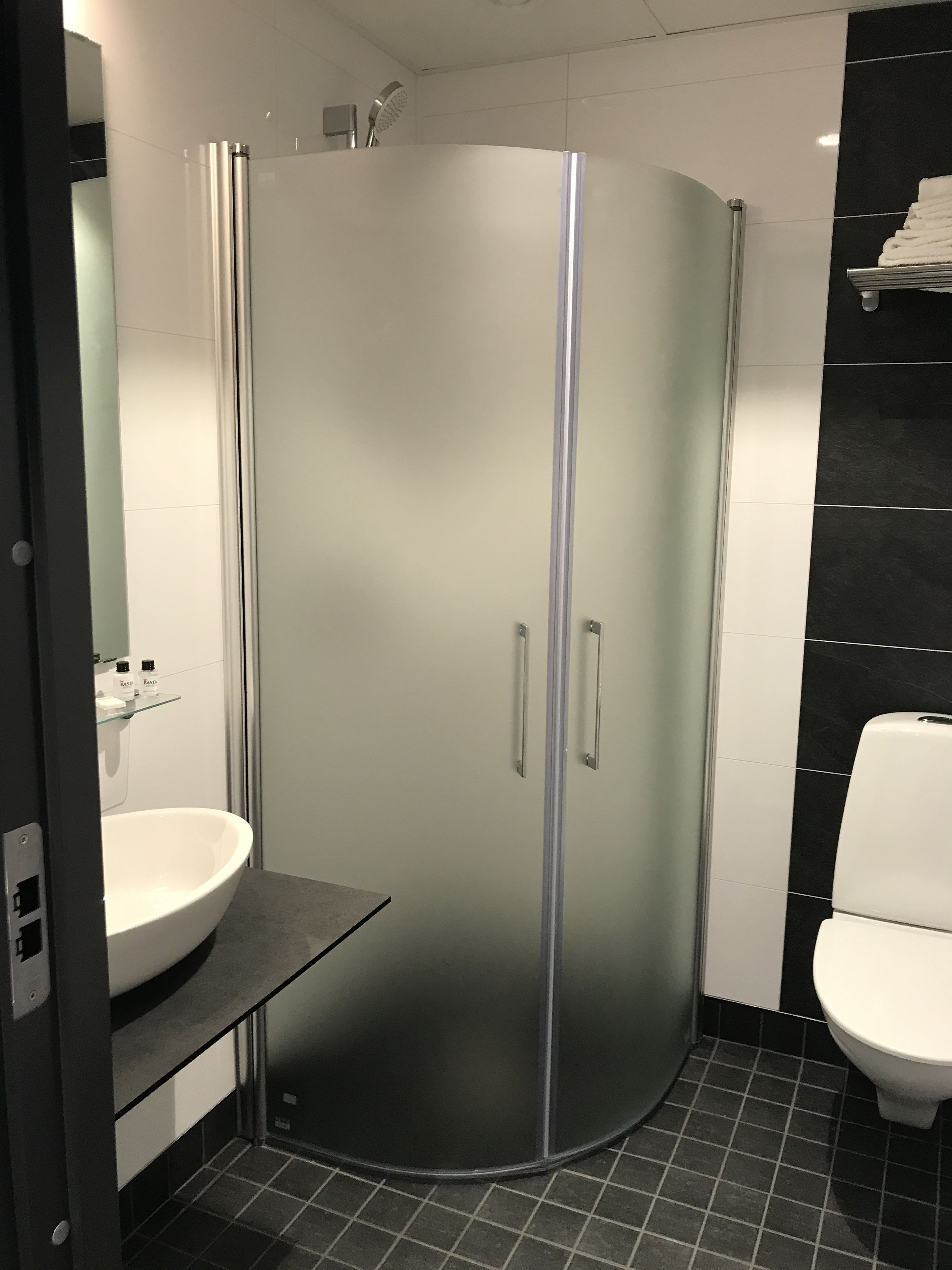Une salle de bain moderne avec une douche à parois de verre, un lavabo blanc et des toilettes.