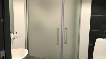 Une salle de bain moderne avec une douche à parois de verre, un lavabo blanc et des toilettes.