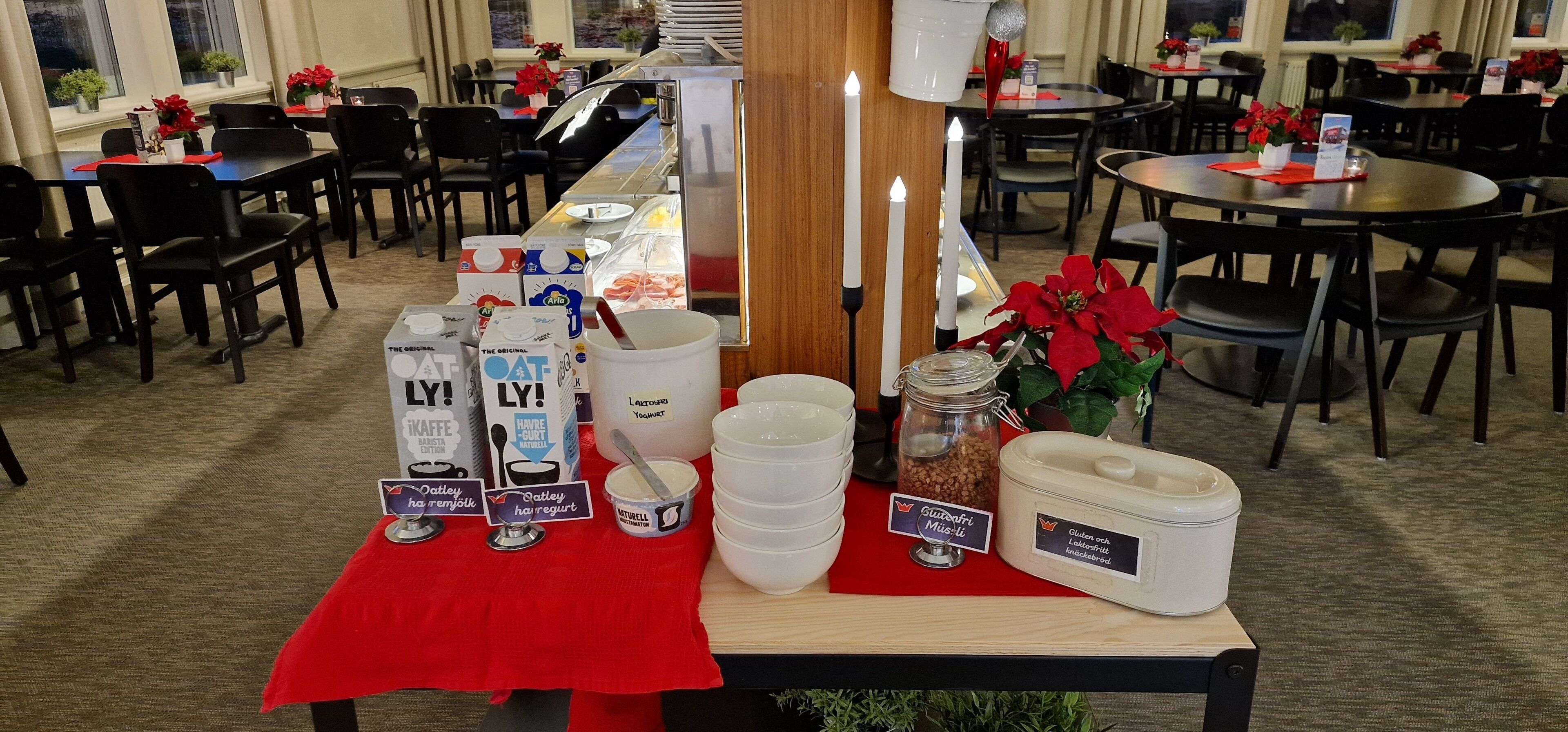 Montaje de bufé con diversos alimentos y recipientes, incluyendo productos lácteos y un tarro de nueces, en un comedor con mesas y sillas.