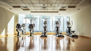 A spacious room with large windows, exercise equipment, and a polished wooden floor. - Piks Key - Marina Torch Tower (Dubai)