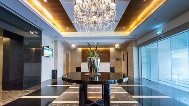 A modern lobby with a round table, a chandelier, and a potted plant. - Piks Key - Marina Torch Tower (Dubai)
