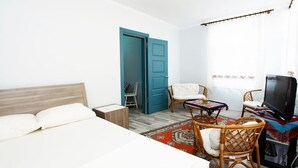 Una habitación de hotel con una cama, una mesita con sillas, un televisor y una puerta azul.