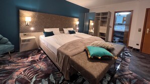 Camera d'albergo con un letto grande, comodini, un armadio e un bagno visibile attraverso una porta aperta.