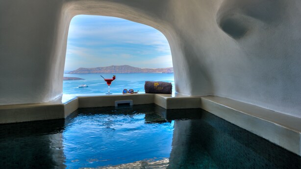 An infinity pool with a clear view of the sea and distant land. - Iriana Suites (Santorini)