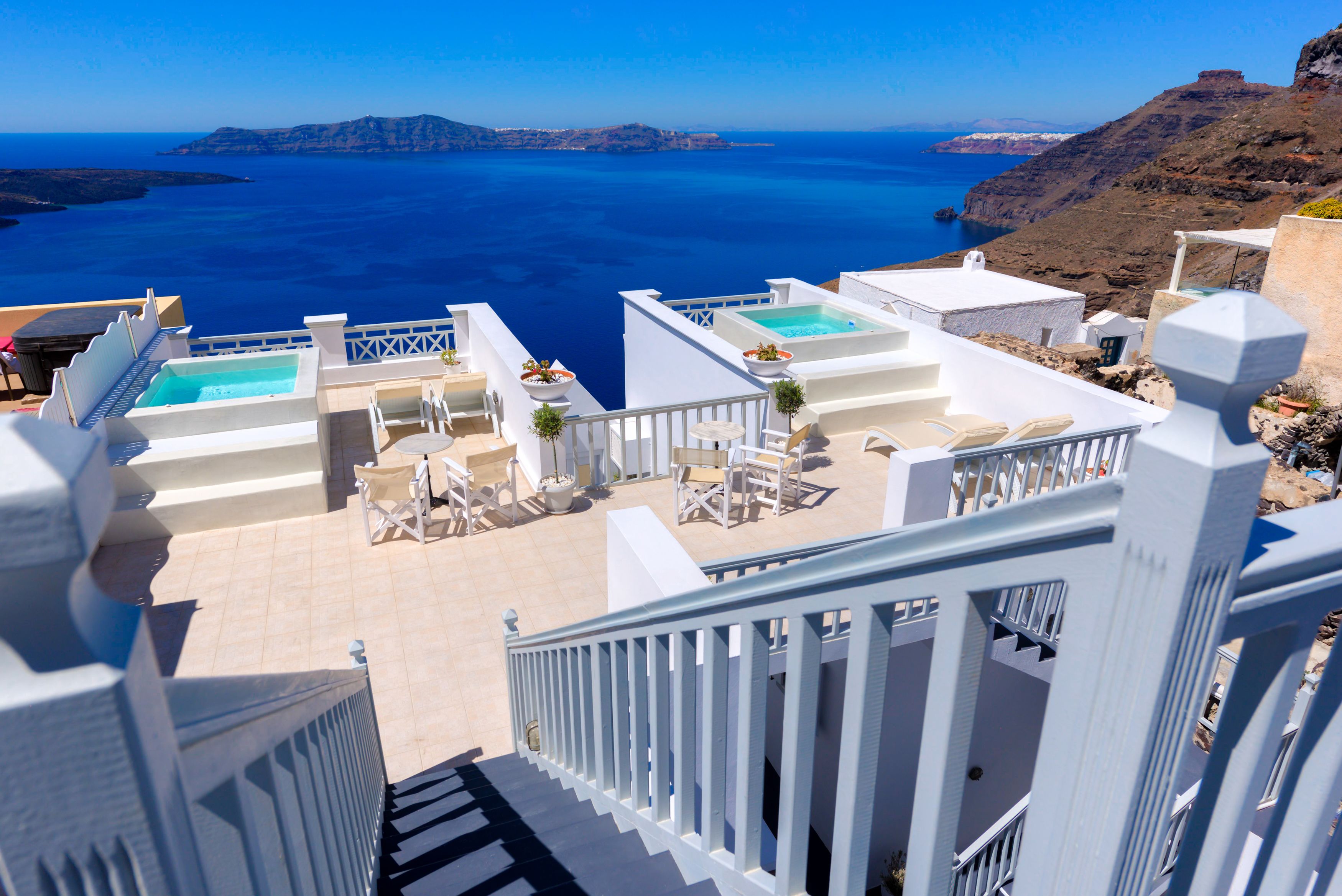 Eine Dachterrasse mit mehreren Liegestühlen und einem Swimmingpool, mit Blick auf eine malerische Küstenlandschaft.