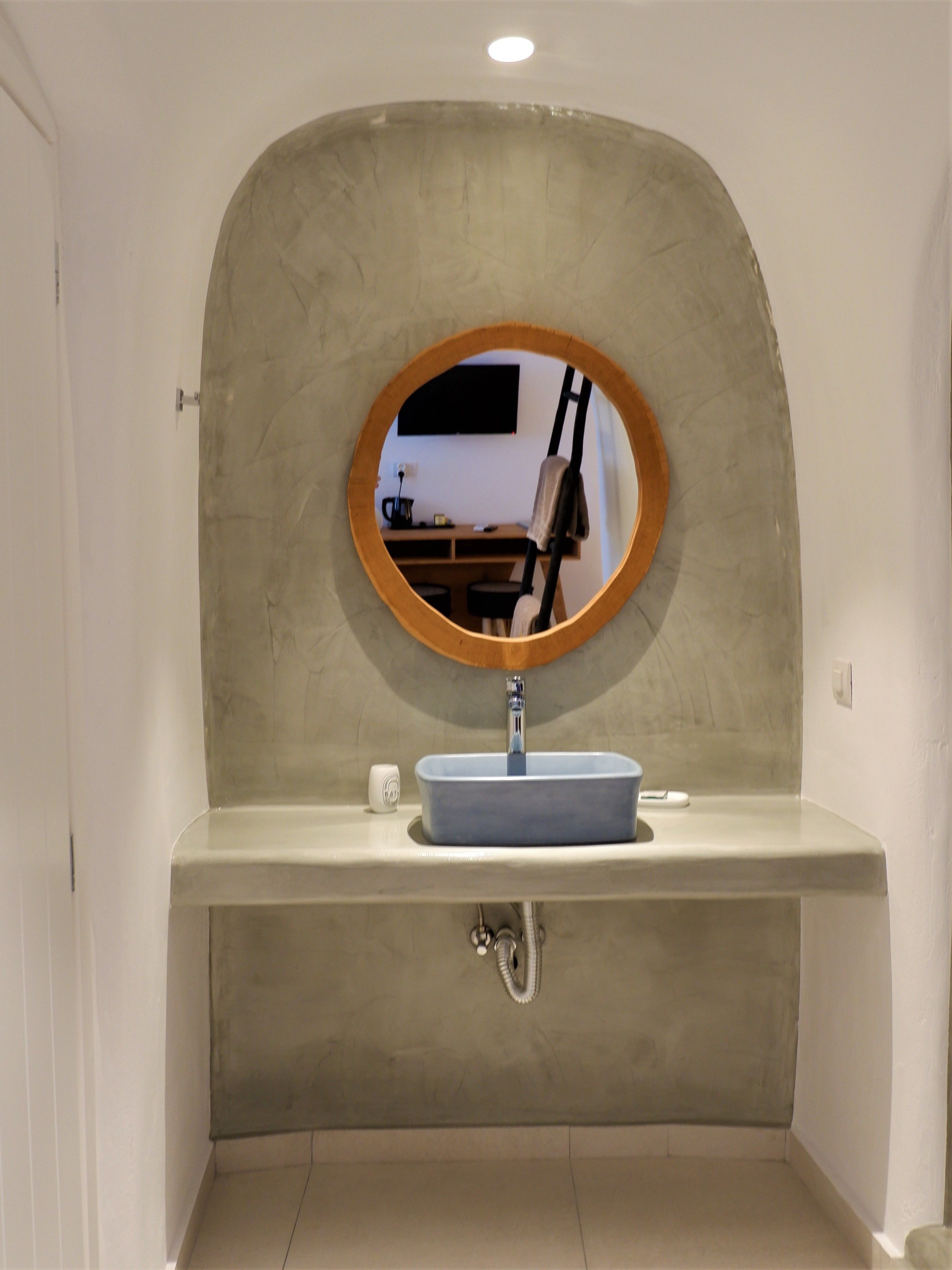 A bathroom with a round mirror, a sink, and a towel rack.
