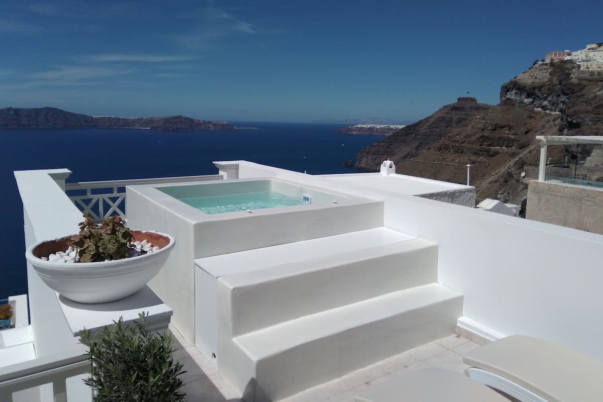 Un edificio blanco con piscina, escalones y vistas al mar.