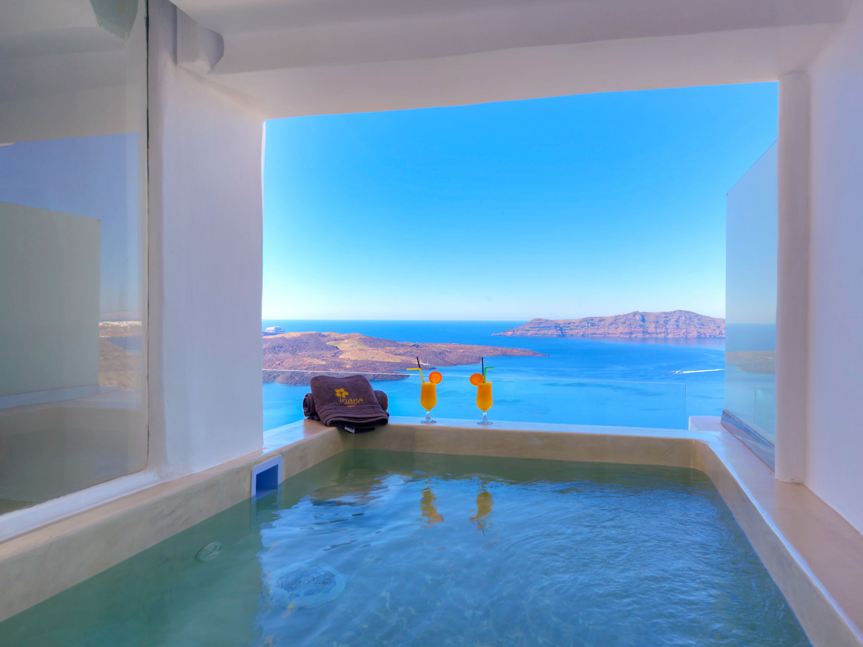 A bathtub with a view of the sea and a towel with a logo.