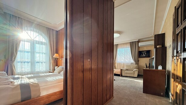 Een hotelkamer met een bed, een houten garderobe, een bank, een bureau en een televisie.