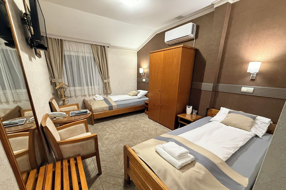 A hotel room with two beds, a wardrobe, a desk with a telephone, and a mirror.