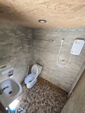 Un baño pequeño con inodoro, lavamanos y cabina de ducha.