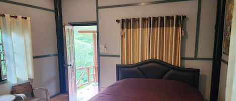 Un dormitorio con cama, una silla, una mesita y una puerta que da a un espacio exterior.