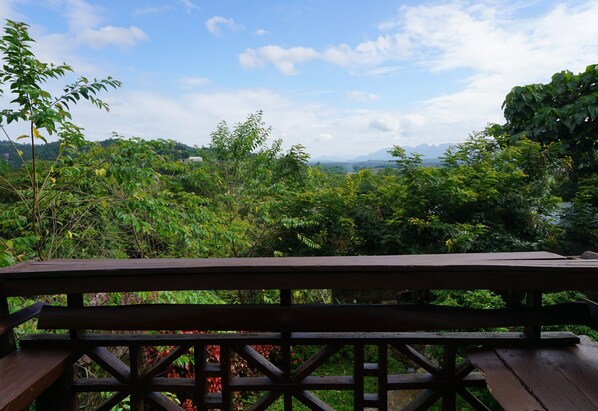 Una terraza de madera con vistas a un paisaje verde exuberante y montañas distantes.