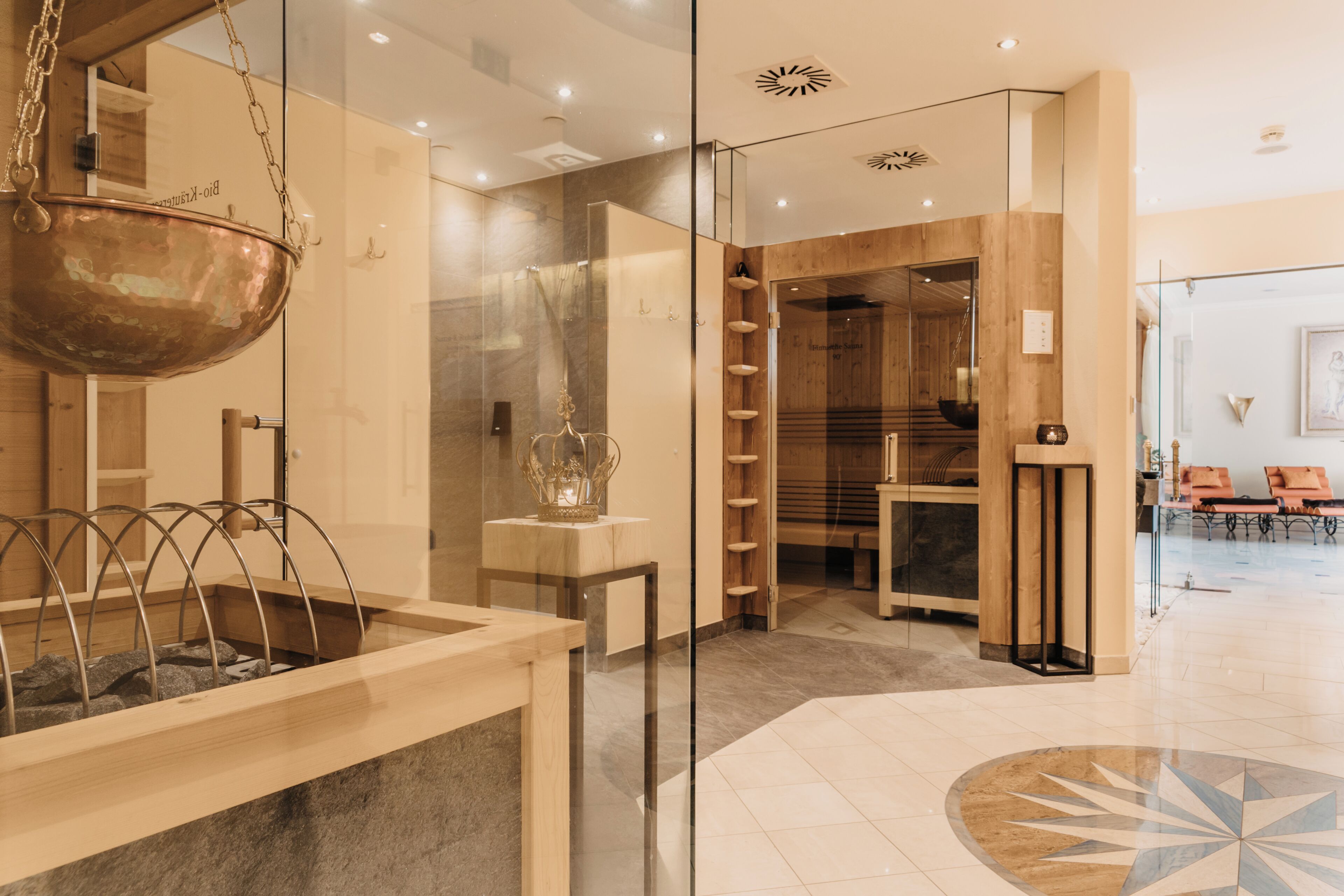 A modern lobby with a glass partition, a hanging copper bowl, and a patterned floor.