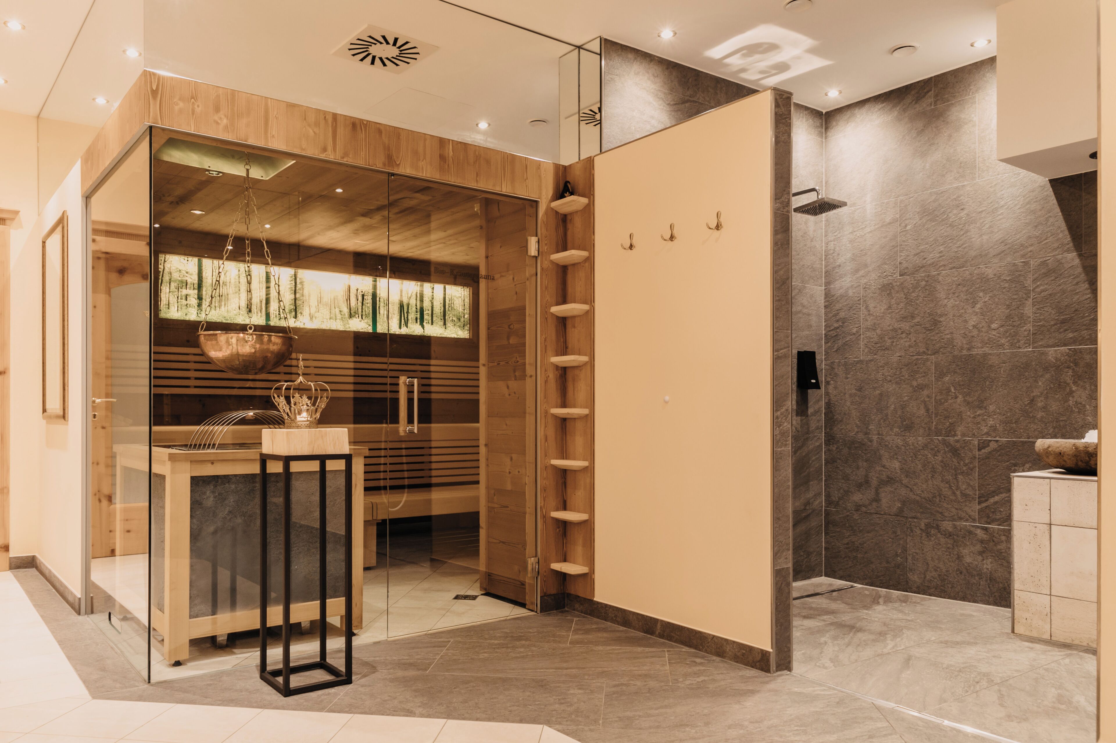 Ein modernes Badezimmer mit einer gläsernen Duschkabine, Holzelementen und einem Boden aus Marmorplatten.