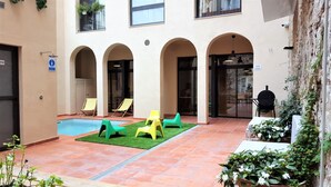 A courtyard with a swimming pool, outdoor seating, and a door marked 'SALIDA'. - Ten To Go Hostel (Barcelona)