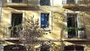 A multi-story building with balconies, windows, and a tree in front. - Ten To Go Hostel (Barcelona)