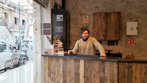 A reception desk with a wooden backdrop, a vase with dried flowers, and a sign indicating a reception opening at 8:00 AM. - Ten To Go Hostel (Barcelona)