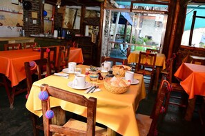 A restaurant with tables covered in yellow tablecloths, wooden chairs, and a rustic interior. - Hostal Yatasto (Salta)