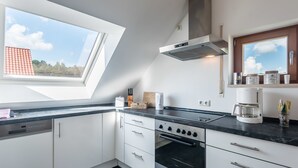 A modern kitchen with a skylight, a stove, and a coffee maker. - Appartmenthaus am Erlbach (Buch am Erlbach)