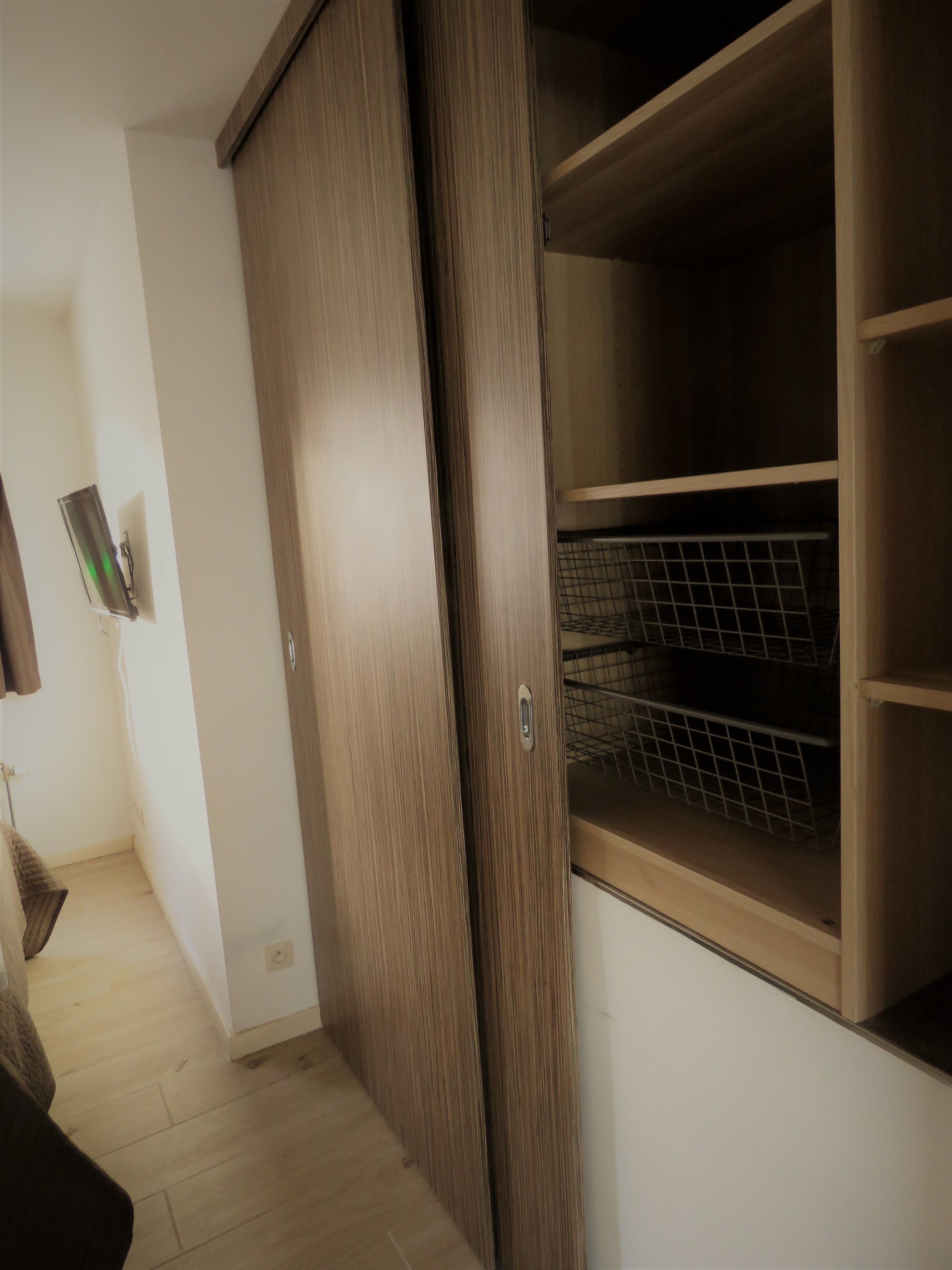 A hallway with a wooden wardrobe and a metal shelf unit.