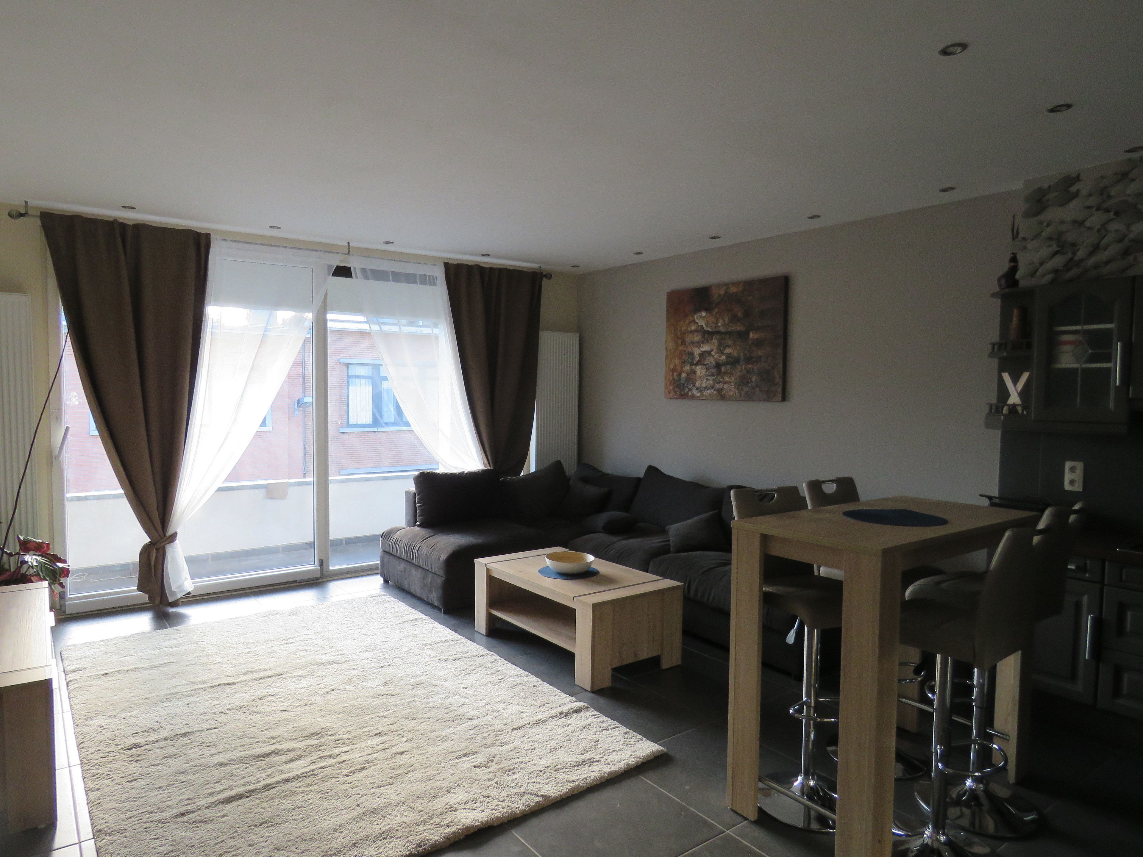 Een moderne woonkamer met een bank, salontafel en een eethoek met stoelen en een tafel.