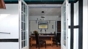 An open door to a dining area with a table and chairs, a hanging light fixture, and a framed picture on the wall. - Vogel Hotel Appartements & Spa (Rostock)