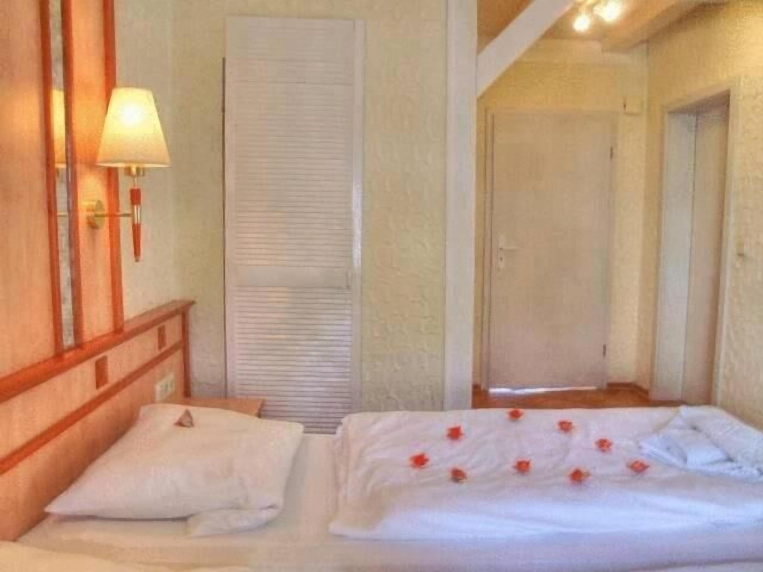 Habitación de hotel con dos camas, una lámpara de noche y una puerta con sistema deslizante.