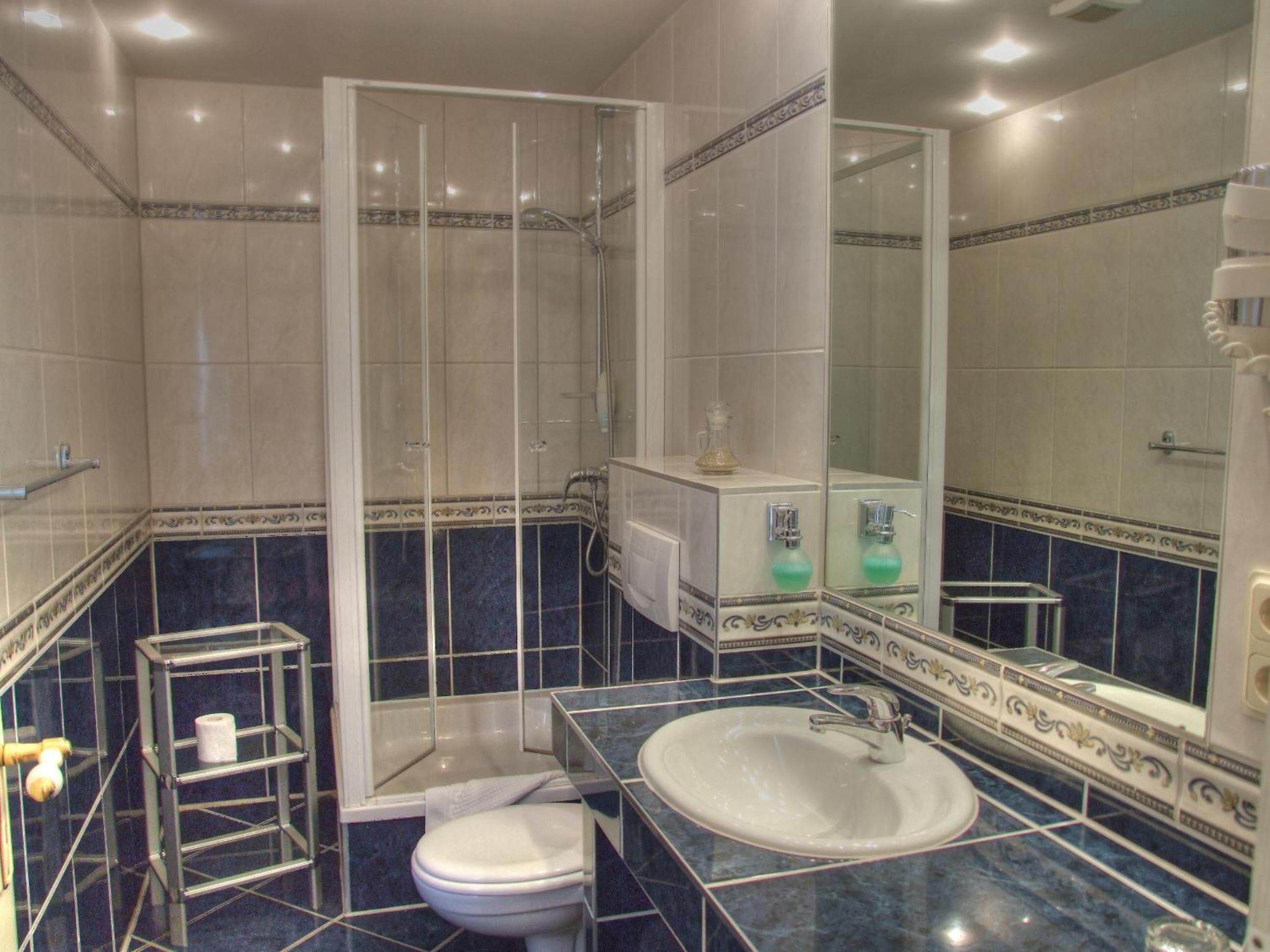 Een badkamer met een douchecabine van glas, een wit wastafelmeubel en een toilet.