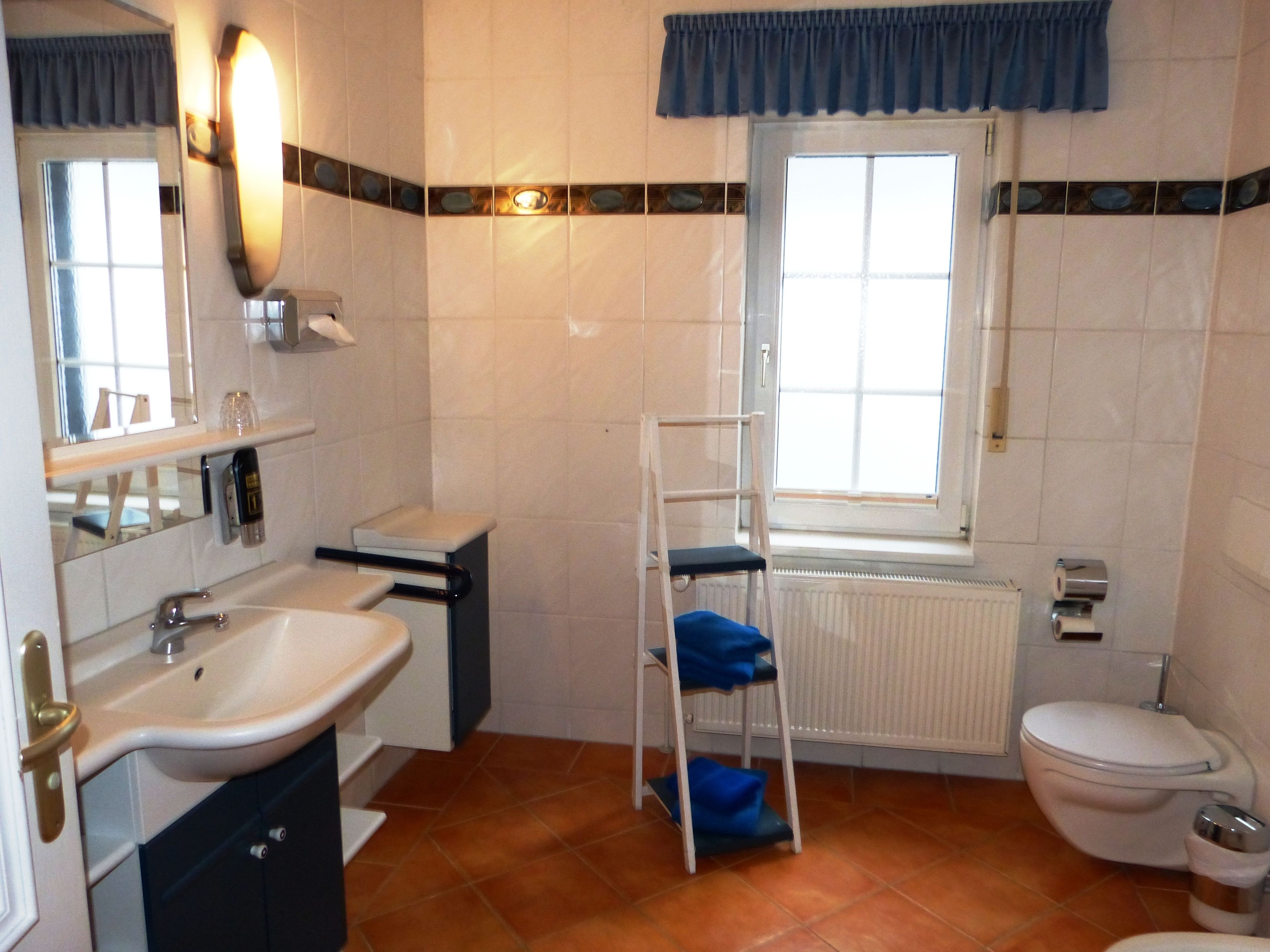 Une salle de bain avec un lavabo, des toilettes et une fenêtre.