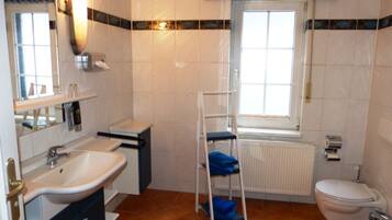 Une salle de bain avec un lavabo, des toilettes et une fenêtre.