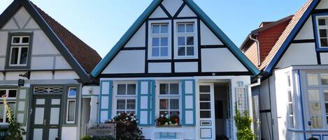 A traditional half-timbered building with a reception area, stone pathway, and potted plants.