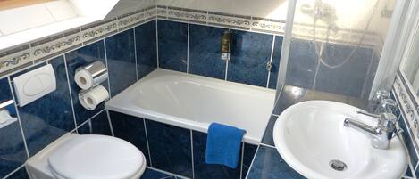 Ein Badezimmer mit Badewanne, Toilette und Waschbecken, alles mit blau gefliesten Wänden und Böden.