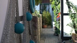 A narrow cobblestone path leading to a building with a white facade and black trim. - Vogel Hotel Appartements & Spa (Rostock)