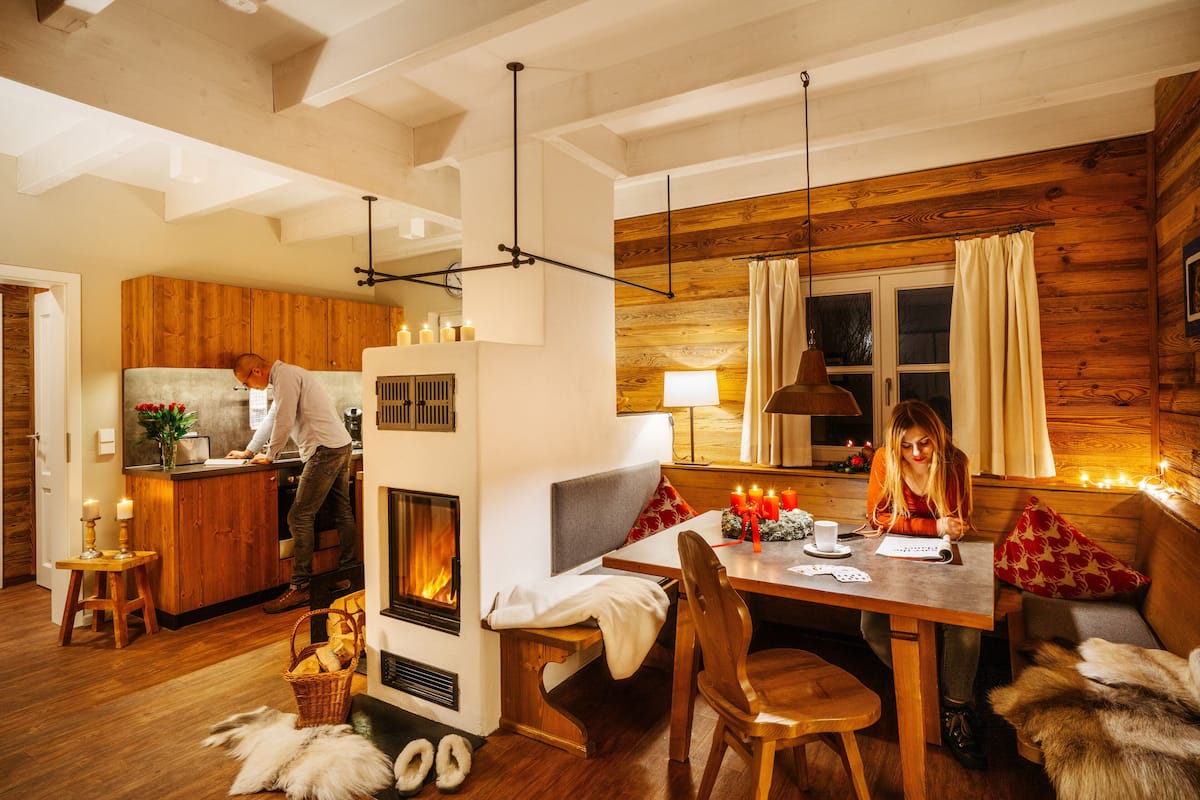 Un intérieur de chalet chaleureux avec une cheminée, des murs en bois, un coin repas et une cuisine.