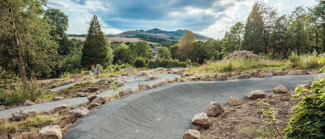 A winding road with large rocks and a view of a hill with a house in the distance.