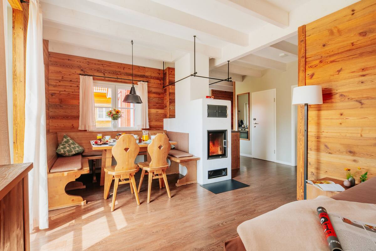 Un salon chaleureux avec une cheminée, des murs en bois et un coin repas doté de meubles en bois.