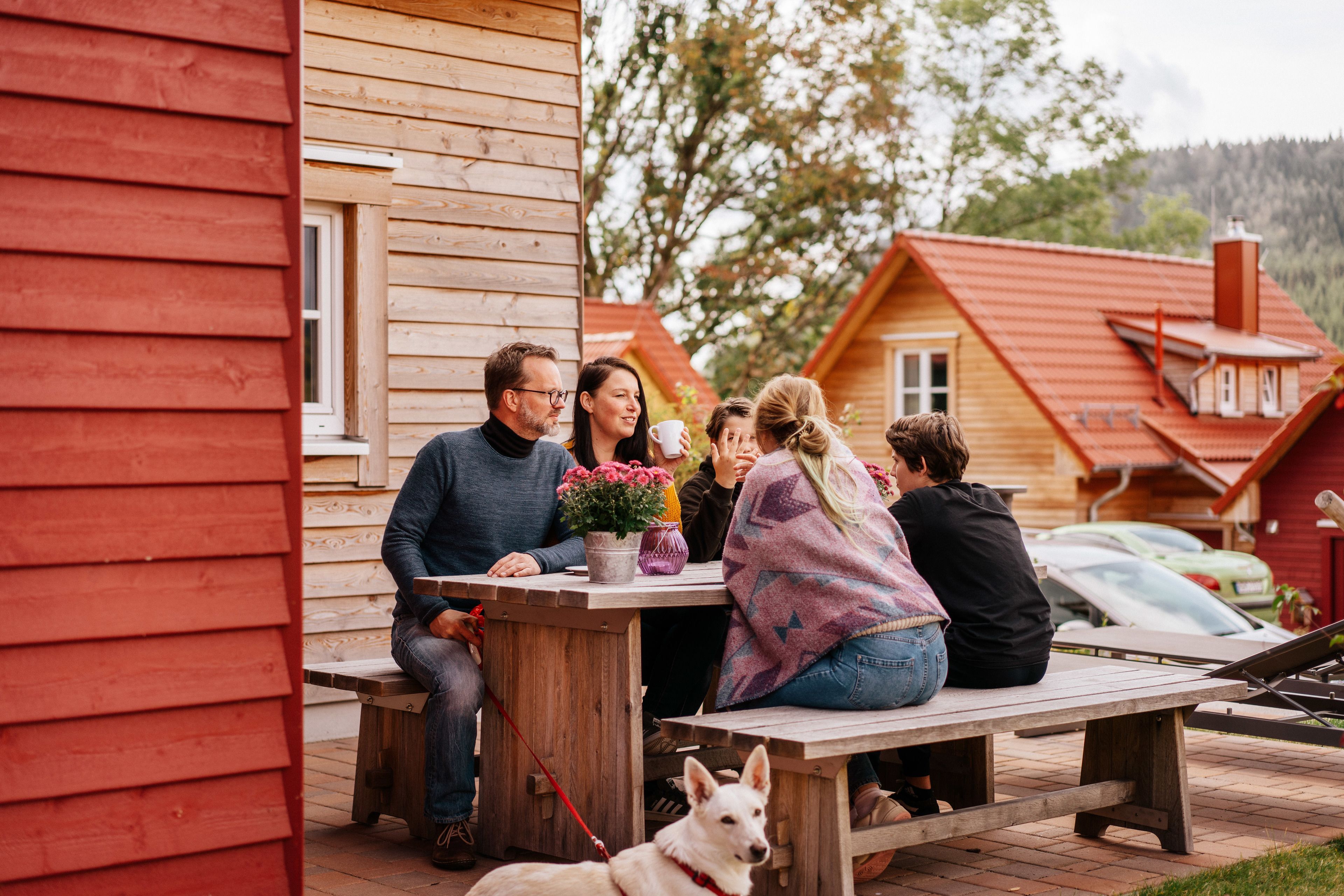 Ein Holzhaus mit roter Fassade, einer Holzterrasse und einem Picknicktisch.