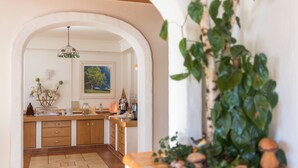 A kitchen with wooden cabinets, a tiled floor, and a hanging light fixture. - Landhaus Bergrast (Ramsau am Dachstein)