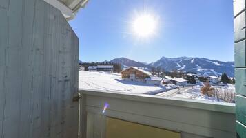 A view from a window overlooking a snowy landscape with mountains in the background.