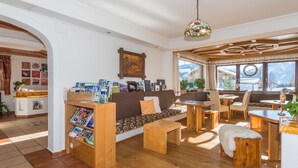 A cozy living room with a wooden sofa, a coffee table, and a dining area with a wooden table and chairs. - Landhaus Bergrast (Ramsau am Dachstein)