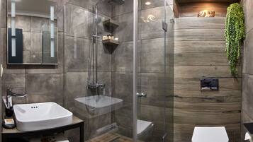 Un baño moderno con ducha de vidrio, lavamanos blanco y retrete.