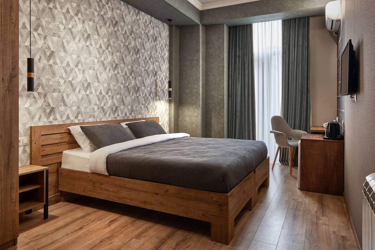 A modern bedroom with a wooden bed, a desk, and a chair.