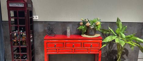 A red telephone booth, a red wooden cabinet with drawers, and a potted plant.