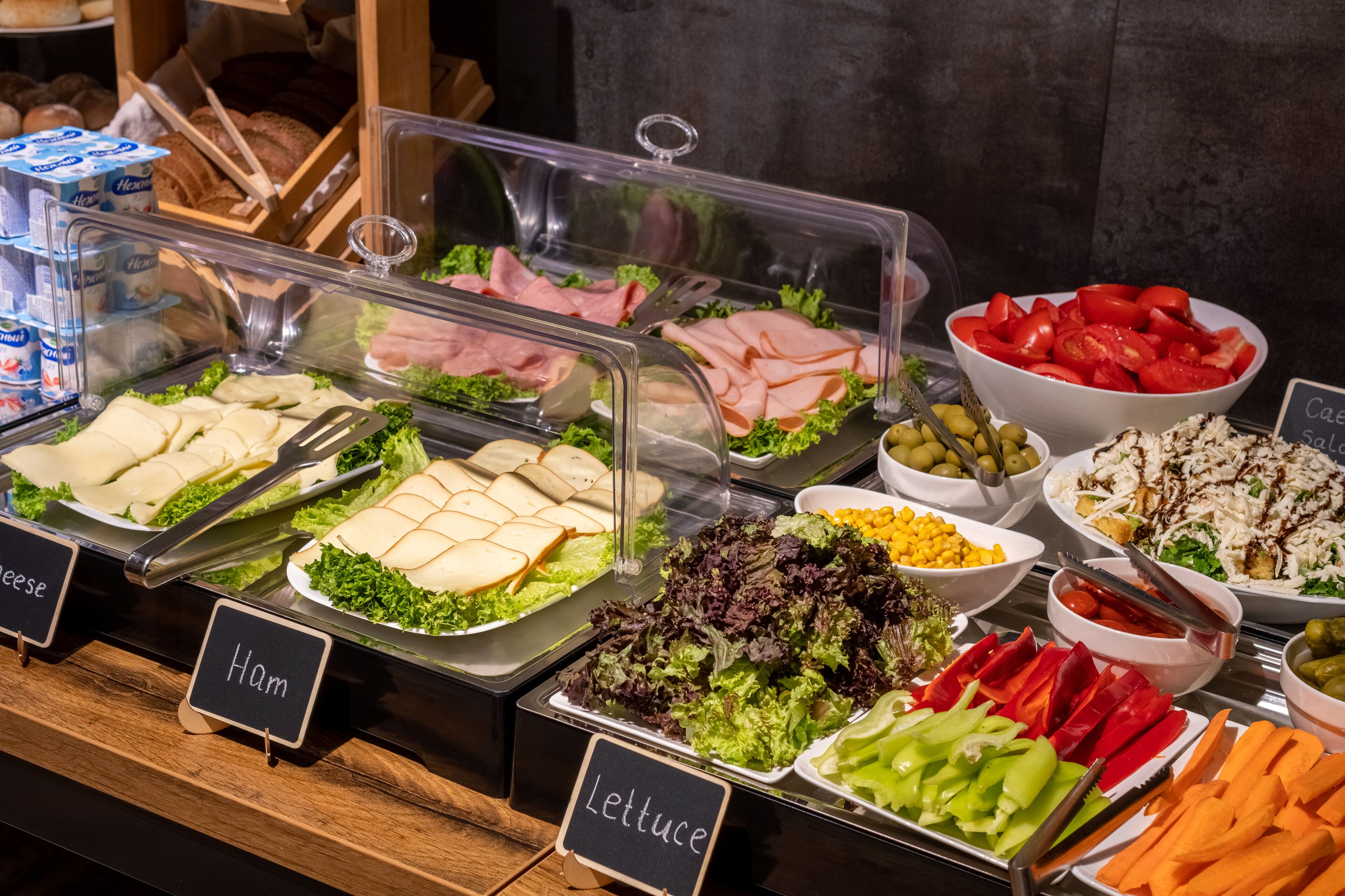 Ein Buffet mit verschiedenen Speisen, darunter Schinken, Käse, Salat und Tomaten.