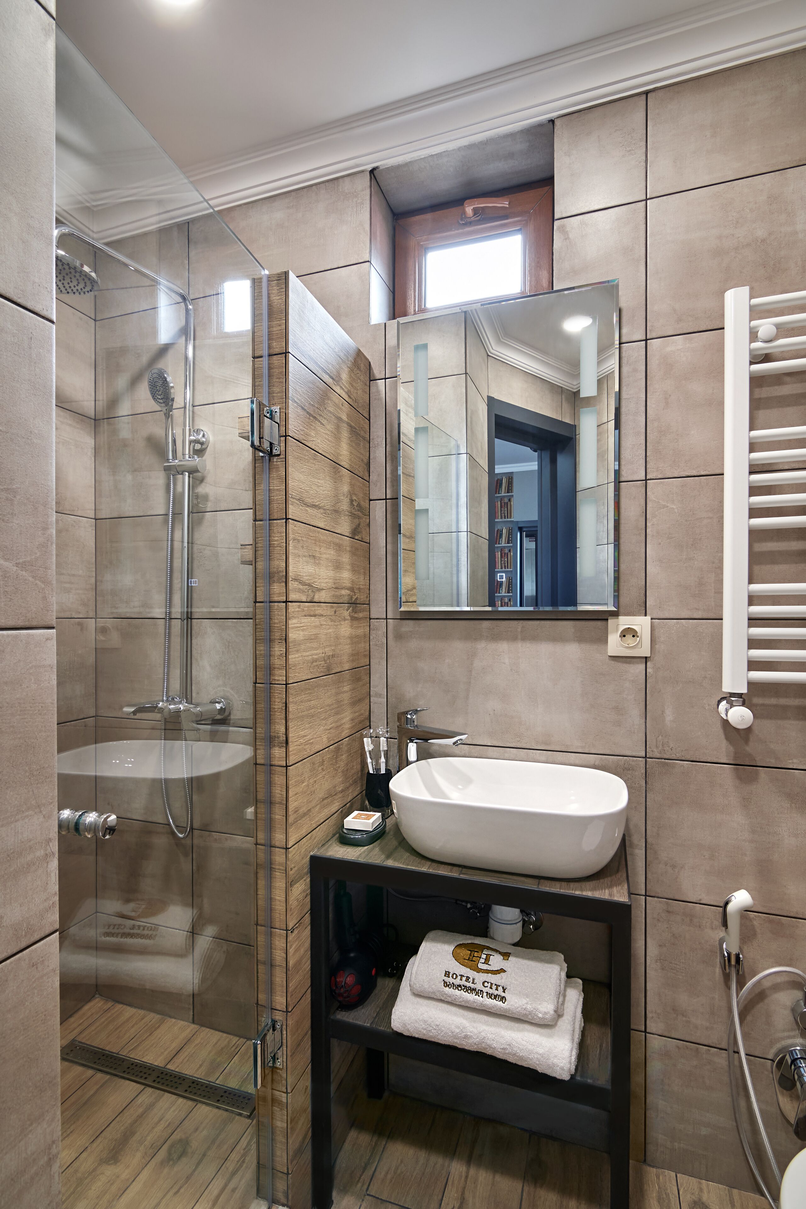A modern bathroom with a glass-enclosed shower, a white sink, and a mirror above it.